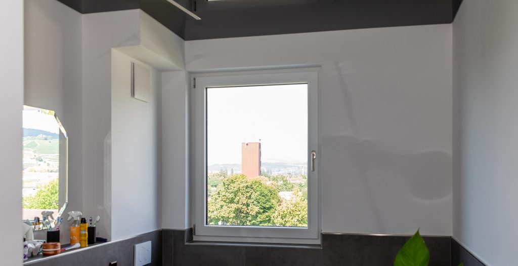 Modernes Badezimmer mit Badlüfter und Fenster als Beispiel für ein kombiniertes Lüftungssystem nach DIN 1946-6.